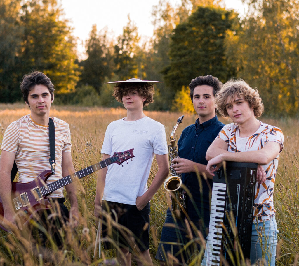 Fyra personer från bandet fotograferade på en äng